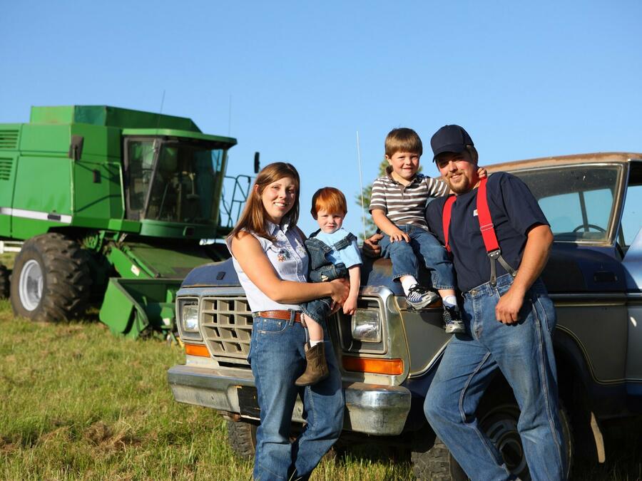 Rural family standing in front of tractor